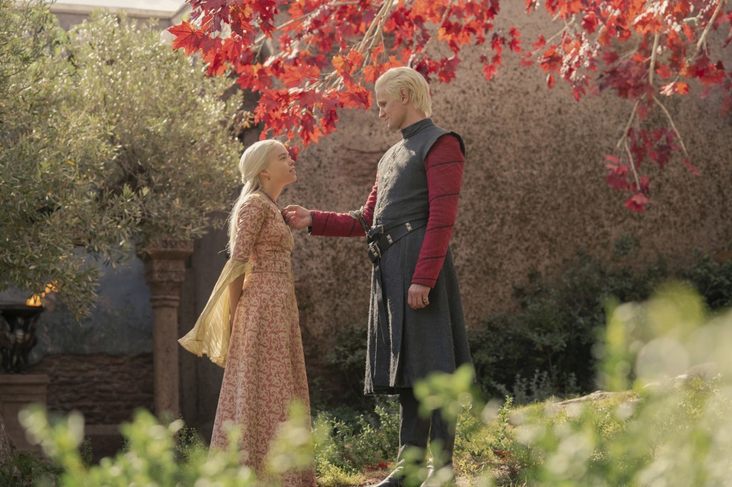 Princess Rhaenyra Targaryen (Milly Alcock) and her uncle, Daemon (Matt Smith) face each other smiling under a tree.
