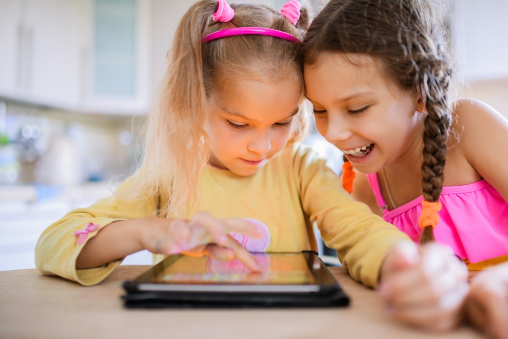 Two kids use an iPad.