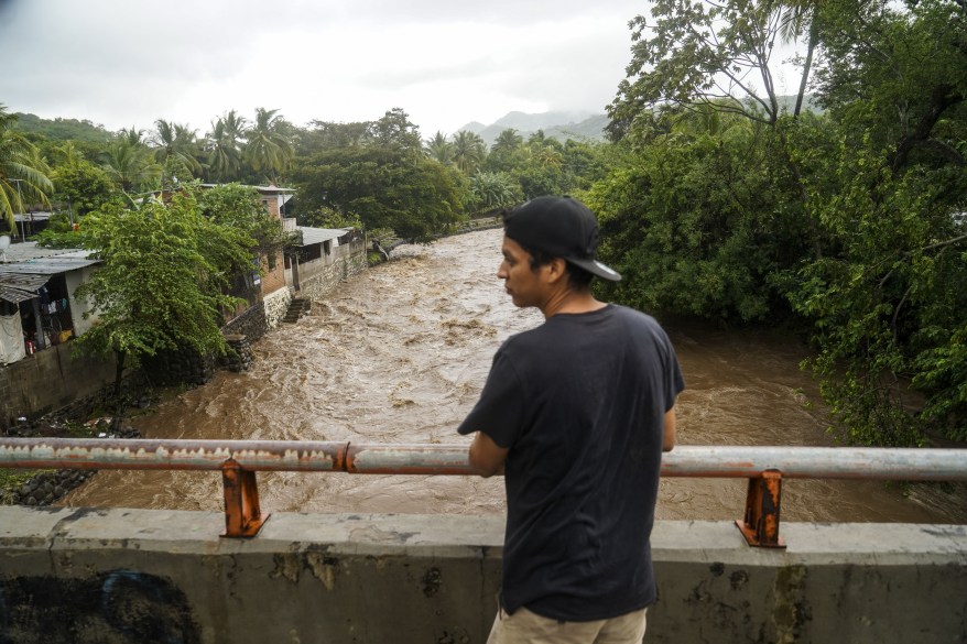 A man observes a flooded river after Hurricane Julia, claiming the lives of 28 people, slammed the area with heavy rains in La Libertad, El Salvador on Oct. 10, 2022.