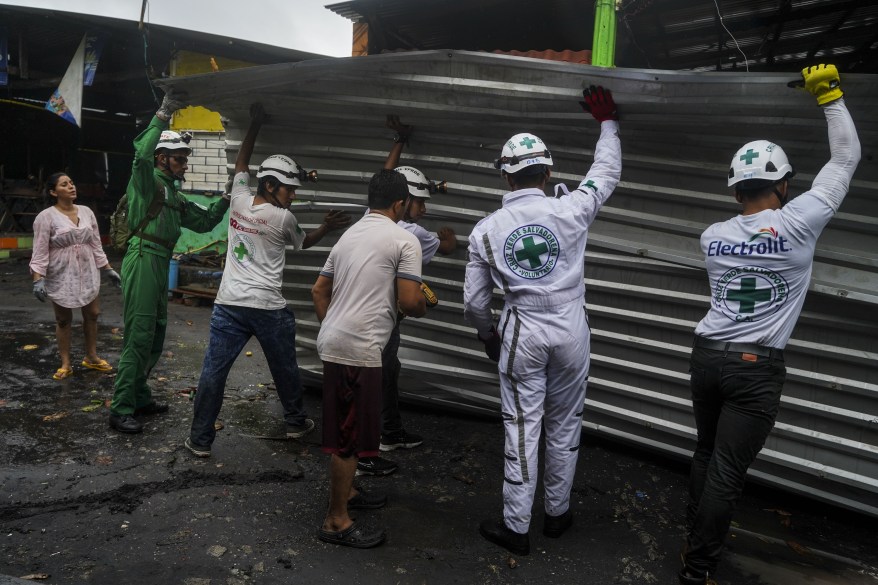 First responders help repair a family's house that collapsed after Hurricane Julia blew strong winds in La Libertad, El Salvador.