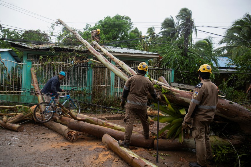 Employees work to clear a street full of downed trees and light poles after the deadly Hurricane Julia demolished the area of Bluefields, Nicaragua.