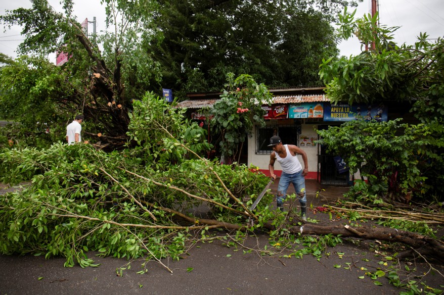 Residents clean debris and cut tree branches outside a damaged house after Hurricane Julia hit the town and dumped heavy rains in La Cruz, Nicaragua pm Oct. 10, 2022.