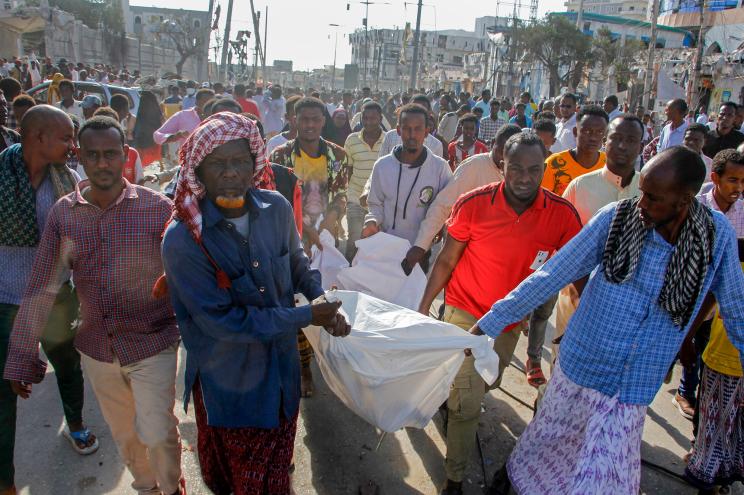 People carry a body away from the rubble after two car bombs went off in Somalia's capital on Saturday, killing at least 100.