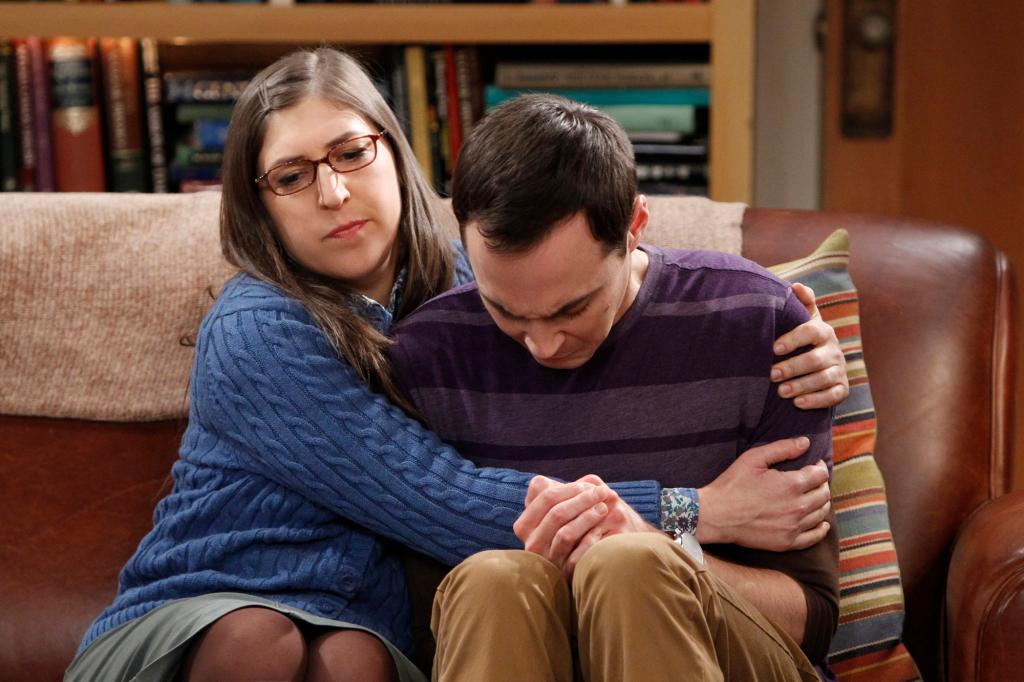 Amy Farrah (Mayim Bialik) and Sheldon Cooper (Jim Parsons) on "The Big Bang Theory" hug on a couch.