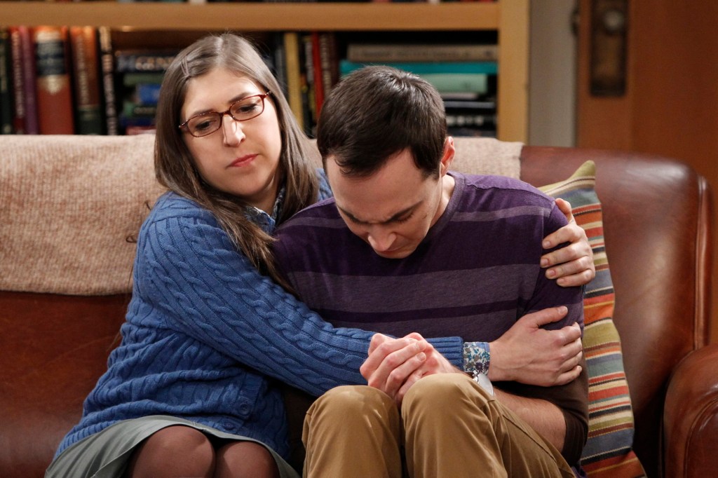 Amy Farrah (Mayim Bialik) and Sheldon Cooper (Jim Parsons) on "The Big Bang Theory" hug on a couch. 