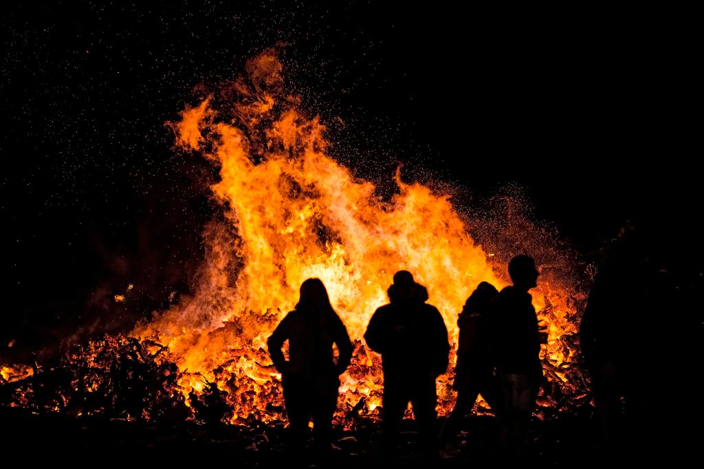 Silhouette of people against large bonfire on bonfire night.