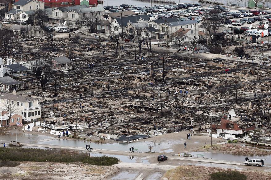 People walk near the remains of burned homes after Hurricane Sandy on Oct. 31, 2012 on Breezy Point.