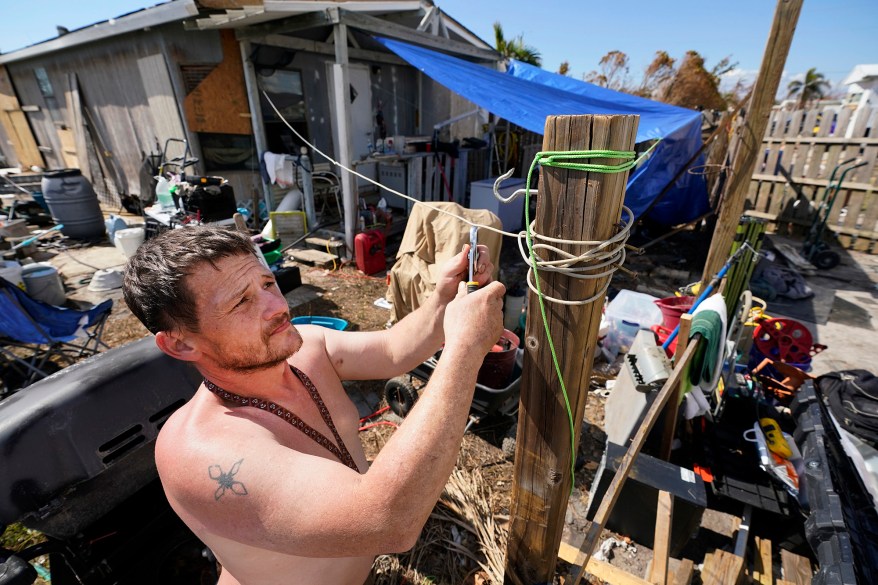 Joe Kuczko puts up a tarp next to his mobile home in Pine Island after Hurricane Ian striked Florida.