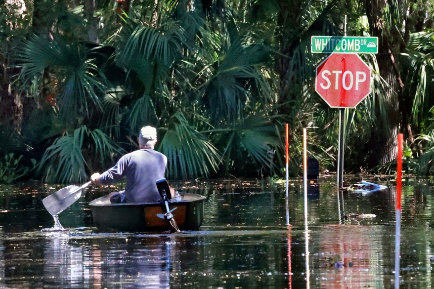 A resident navigates a canoe to his flooded home on Whitecomb Drive along the shore of Lake Harney in Geneva, Florida.