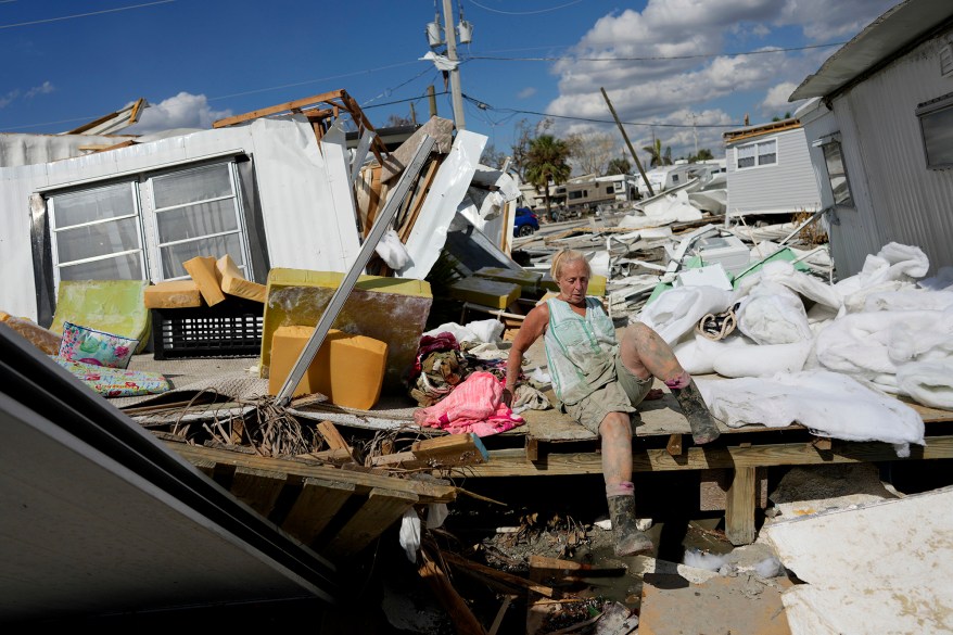 Kathy Hickey, 70, climbs across a ruined trailer as she picks her way through debris to where she and her husband Bruce had a winter home, a trailer originally purchased by Kathy's mother in 1979, on San Carlos Island.