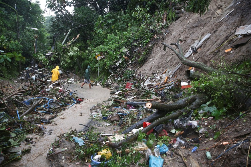 Residents clean a mudslide on a road following the powerful Hurricane Julia that brought strong winds and heavy rain in San Salvador, El Salvador on Oct. 10, 2022.