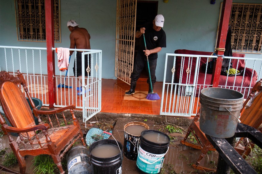 A man cleans mud from in front of his home after Hurricane Julia hit the town and dumped heavy rains in La Cruz, Nicaragua on Oct. 10, 2022.