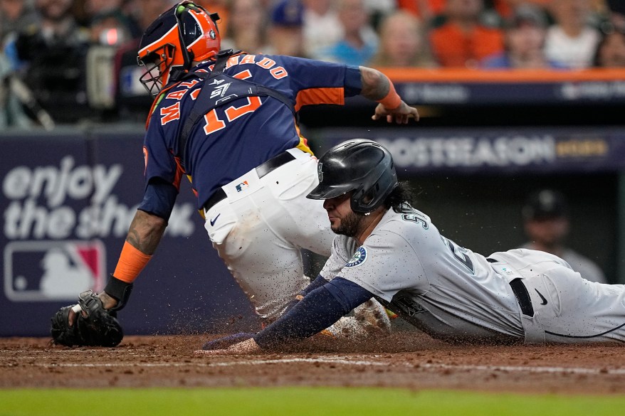 The Seattle Mariners' Eugenio Suarez scores as the Houston Astros' Martin Maldonado misses the throw during ALDS Game 2 game on Oct. 13, 2022 in Houston.