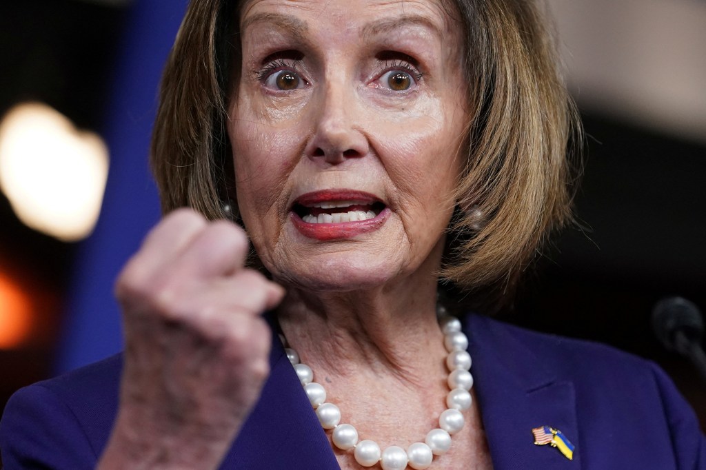 House Speaker Nancy Pelosi shown from the shoulders up with her fist raised.
