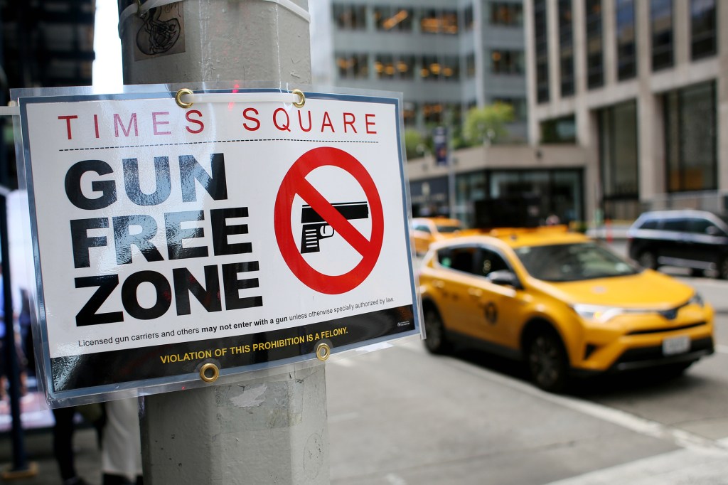 A picture of a gun free zone sign on a pole in NYC.