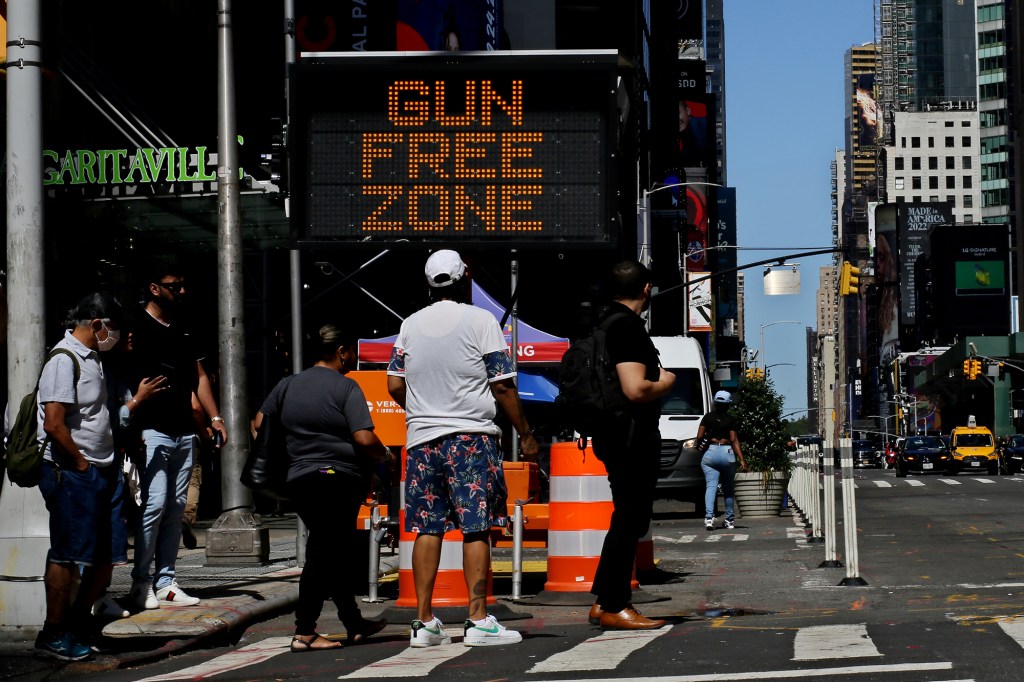 A picture of people making their way near a Gun Free Zone signboard in NYC.