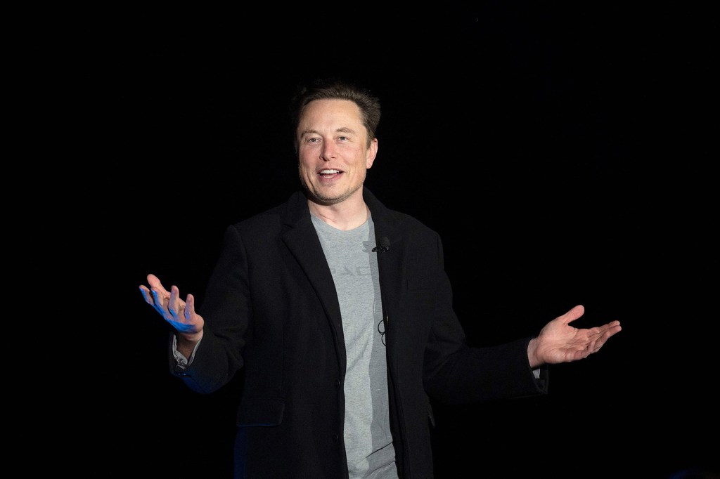 Elon Musk with his hands raised 