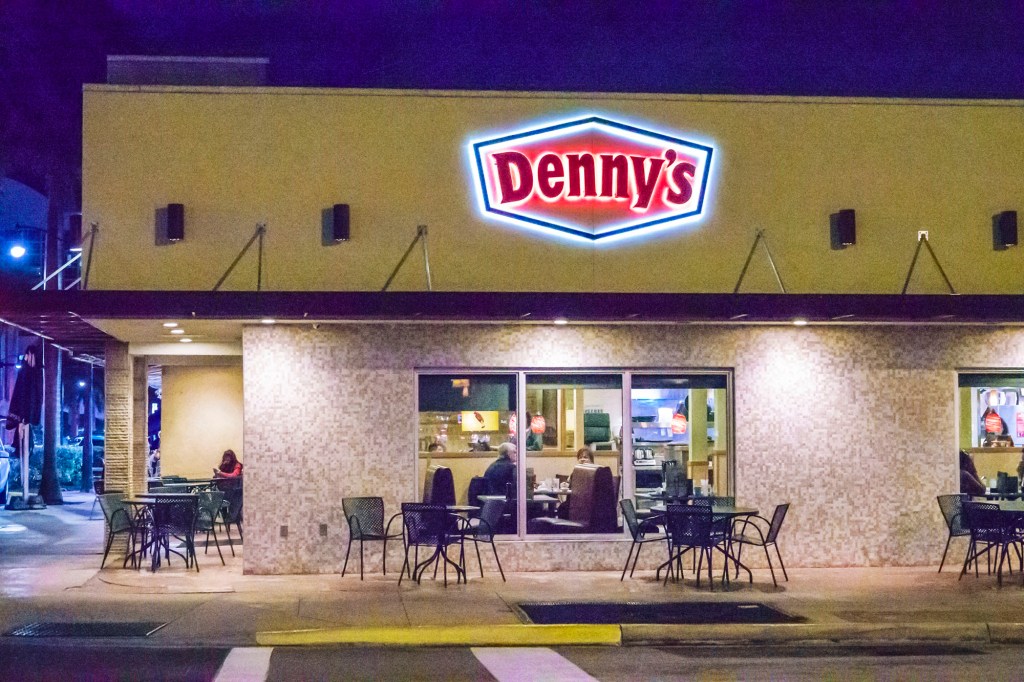 A Denny's lit up at night time.