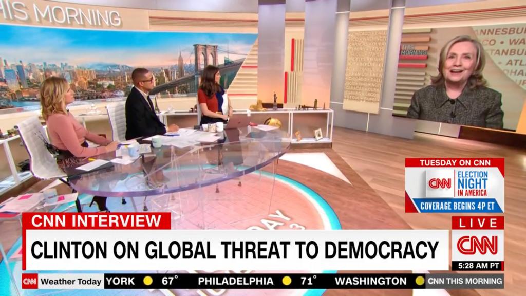 On set with Don Lemon, Kaitlan Collins and Poppy Harlow. The three hosts are conducting a video interview with Hillary Clinton whose image appears on a large screen.