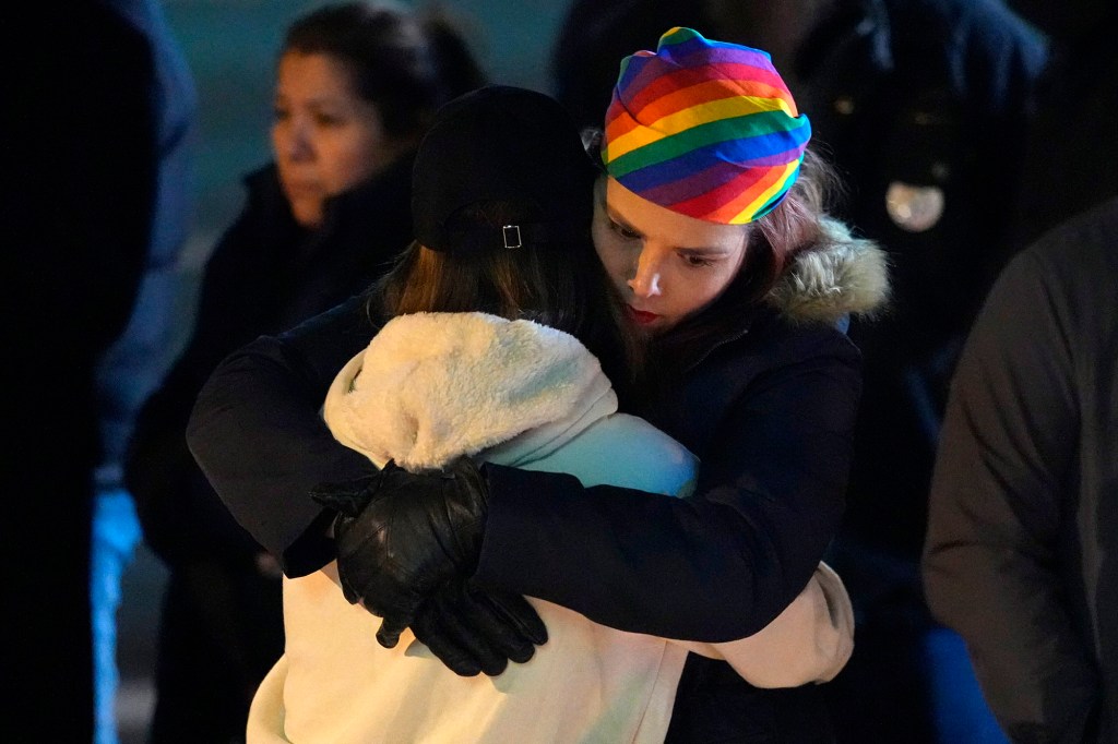 People embrace during a candlelight vigil on a corner near the site of the shooting.