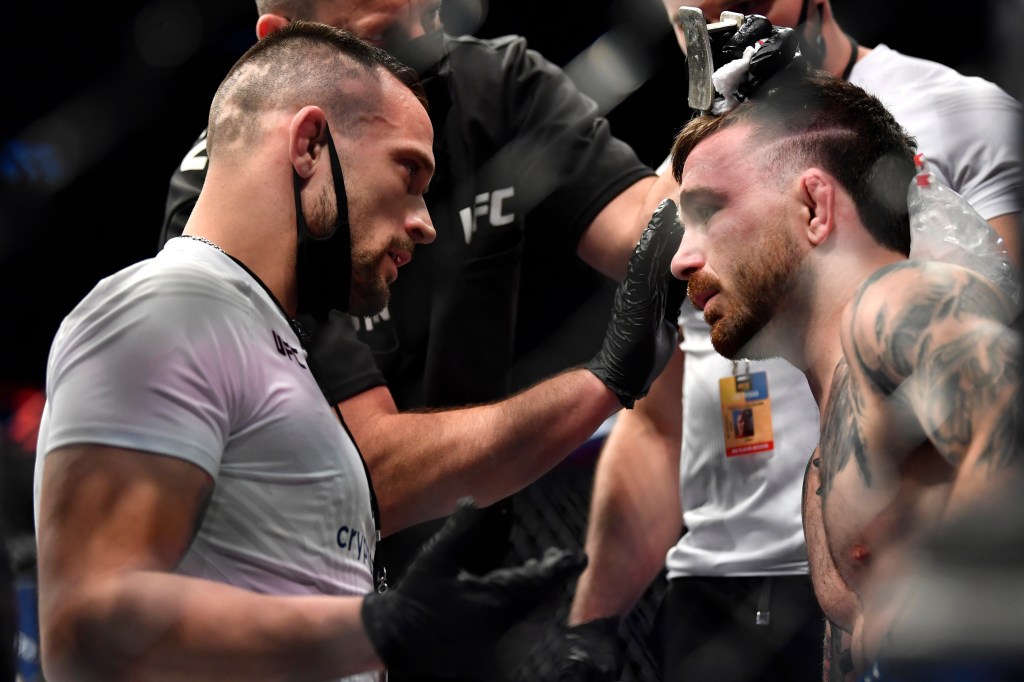 Coach James Krause provides instruction to Darrick Minner in the corner between rounds of his featherweight bout during UFC 269