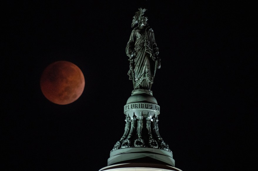 A Beaver Blood Moon Lunar Eclipse is seen behind the Statue of Freedom atop the dome of the US Capitol Building as it sets on Nov. 8, 2022 in Washington, DC.