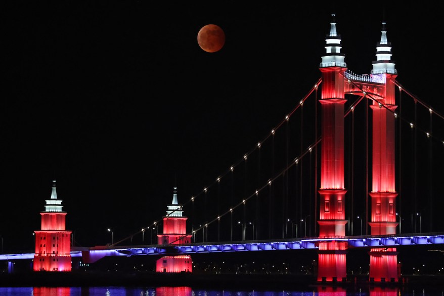 The moon rises above Gangdao Bridge during a total lunar eclipse on Nov. 8, 2022 in Zhoushan, Zhejiang Province of China.