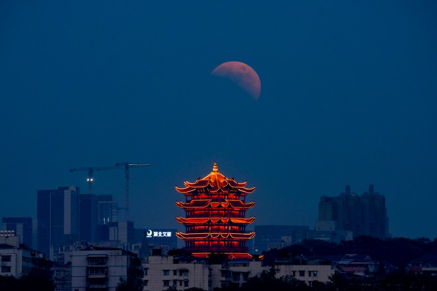 The moon rises above a tower during a total lunar eclipse on Nov. 8, 2022 in Wuhan, Hubei Province of China.