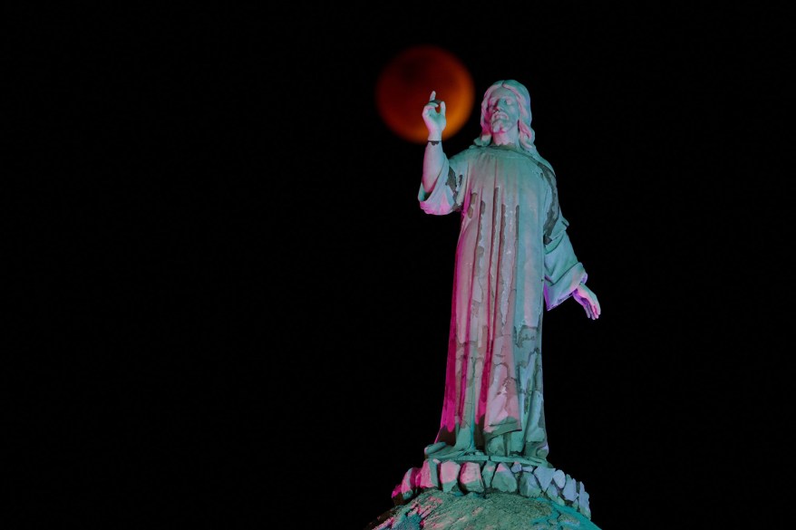 The moon and a statue are seen during a lunar eclipse in San Salvador, El Salvador on Nov. 8, 2022.