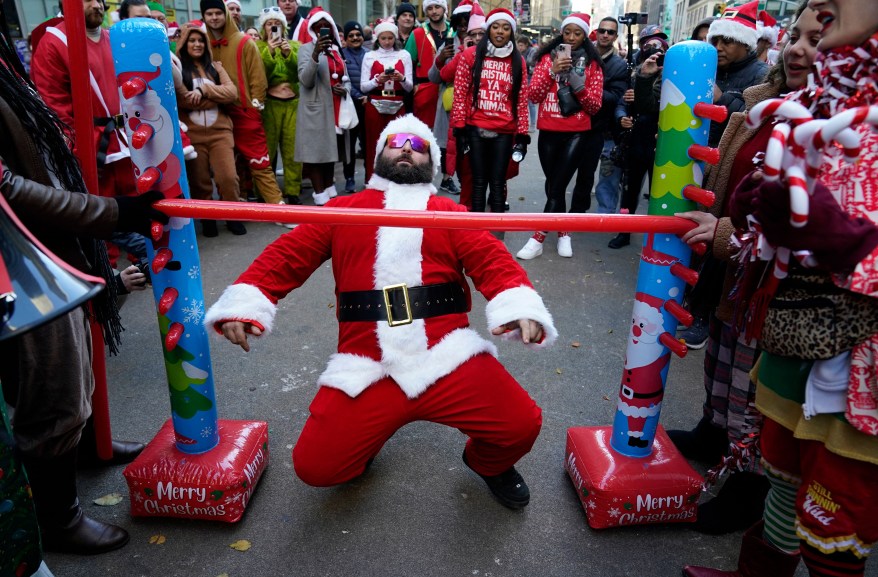 A man dressed in a Santa outfit does the limbo during Santa Con 2022 on Saturday, Dec. 10.