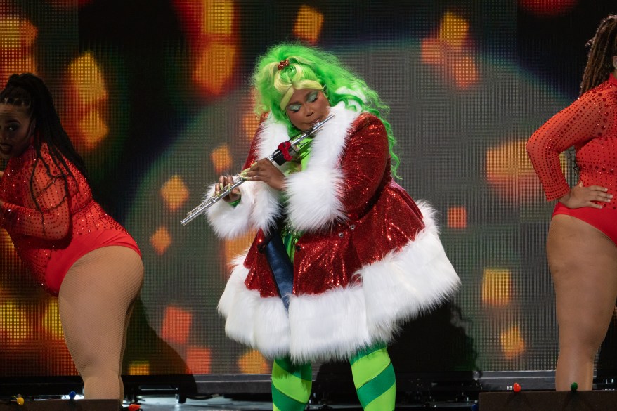 Lizzo, dressed in a festive coat, plays the flute during Z100's Jingle Ball on Friday, Dec. 10, 2022.