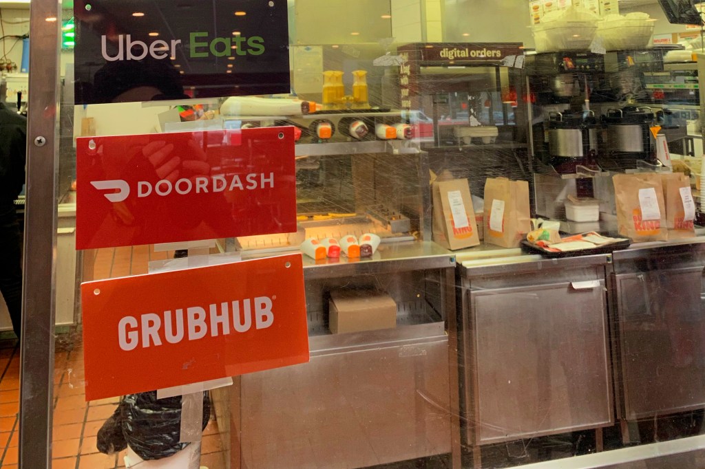 A restaurant with three signs for UberEats, Doordash and Grubhub.