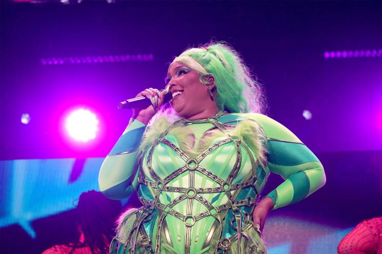 Lizzo, decked out in a green outfit, sings onstage.