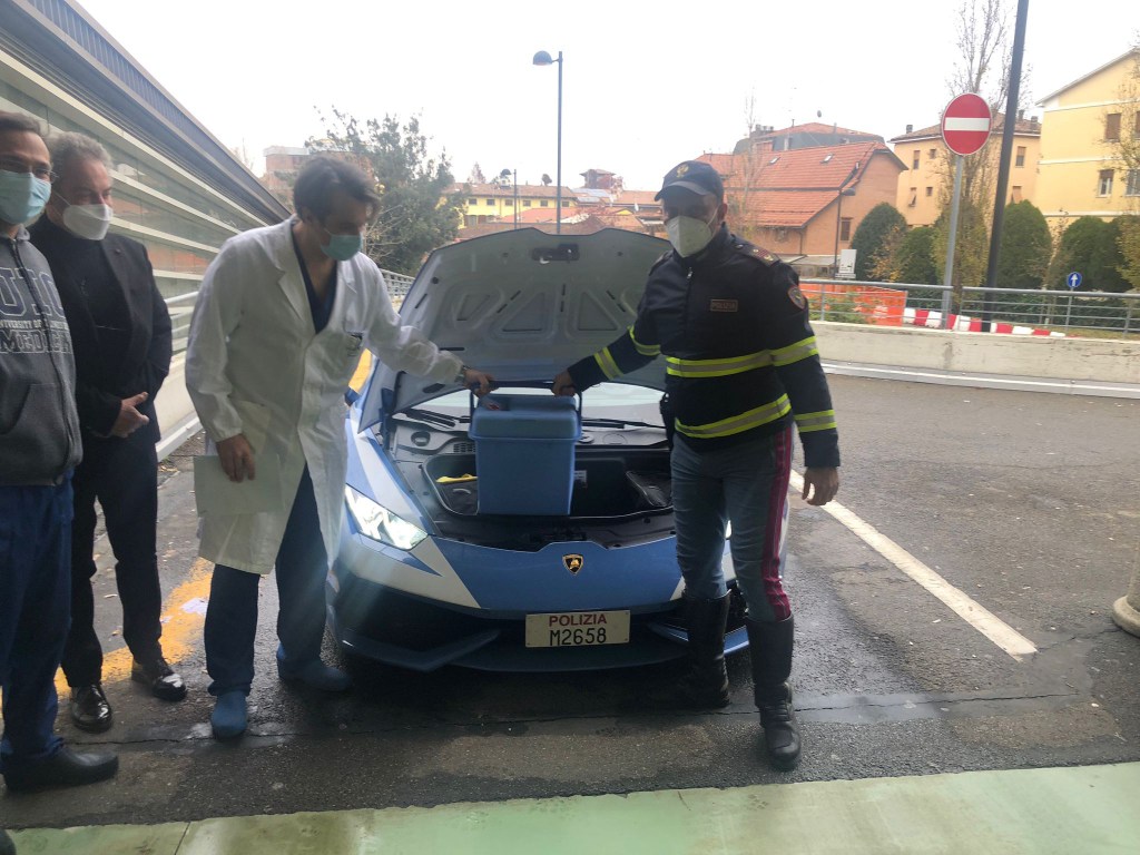 A police officer and a hospital worker unloading the "special cargo" from the Lamborghini police car.  