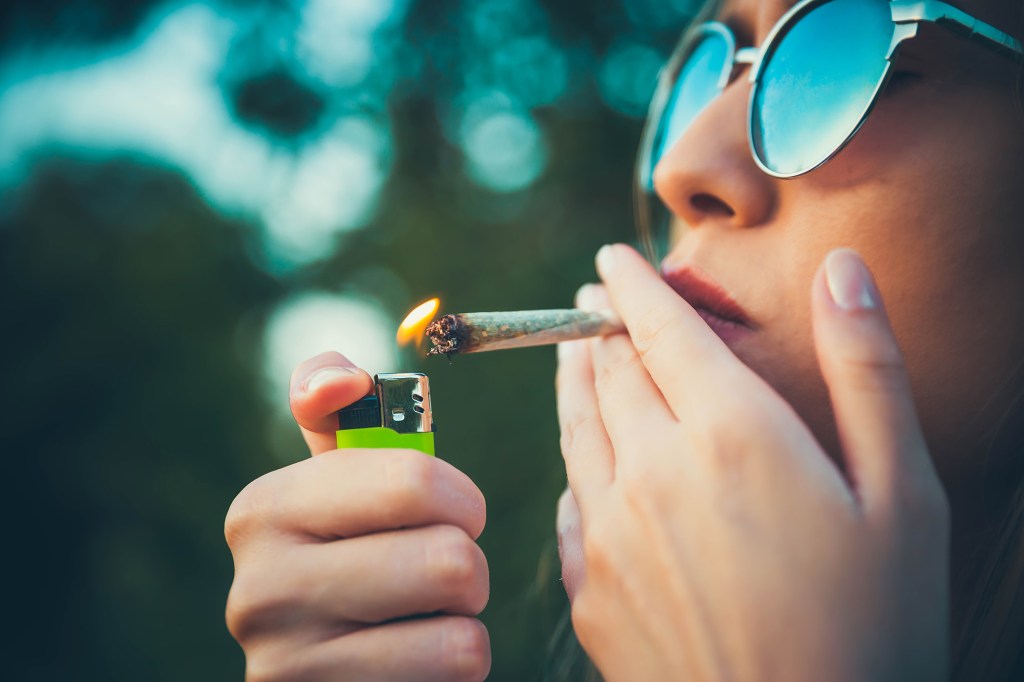 A picture of a woman lighting a hand-rolled cannabis cigarette