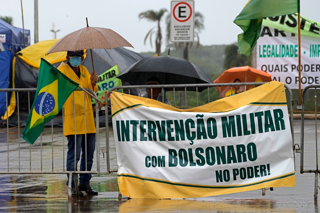 A supporter of outgoing President Jair Bolsonaro display banner with a message that reads in Portuguese "Military Intervention with Bolsonaro in Power"