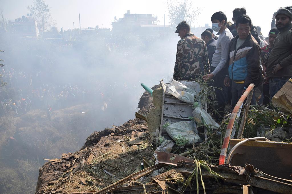 Nepalese rescue workers and civilians gather around the wreckage of a passenger plane that crashed in Pokhara, Nepal, Sunday, Jan. 15,