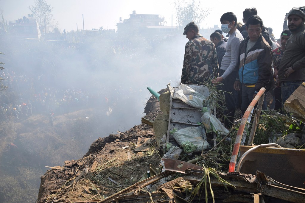 Nepalese rescue workers and civilians gather around the wreckage of a passenger plane that crashed in Pokhara, Nepal, Sunday, Jan. 15, 