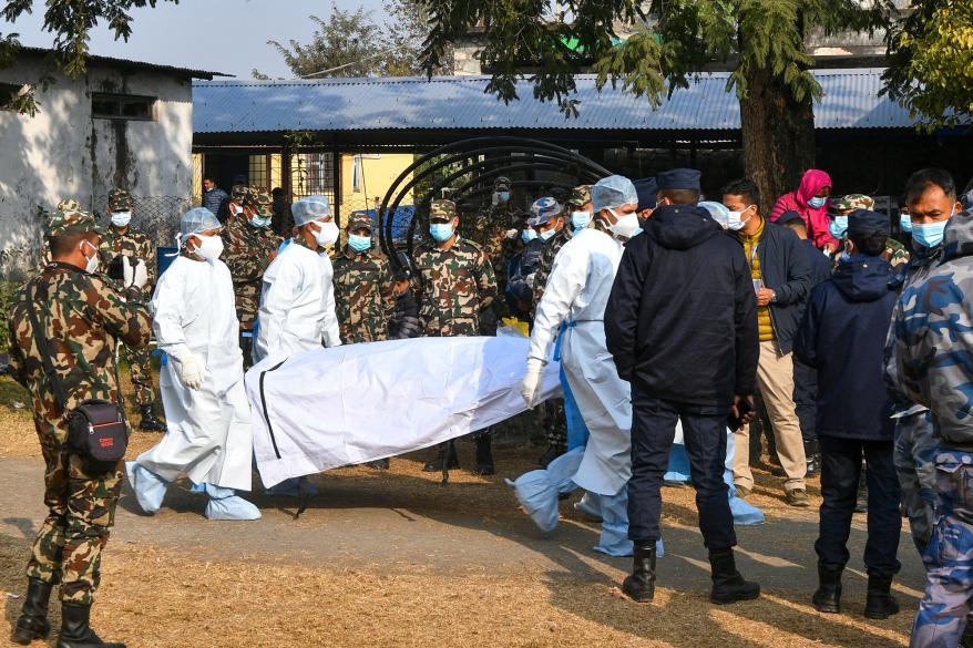 Nepal's army and volunteers carry the body of a victim who died in a Yeti Airlines plane crash in Pokhara.