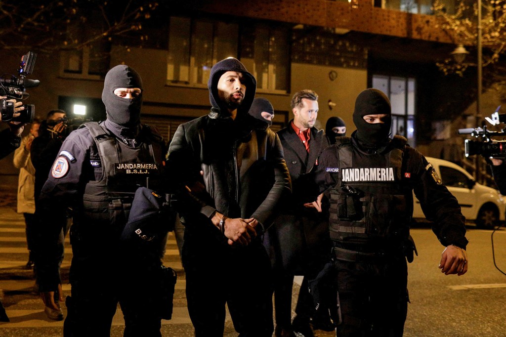 Andrew Tate and brother Tristan Tate are pictured hadcuffed outside headquarters in Bucharest.