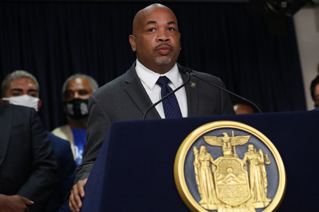 Carl Heastie in a suit behind a podium with a dark background