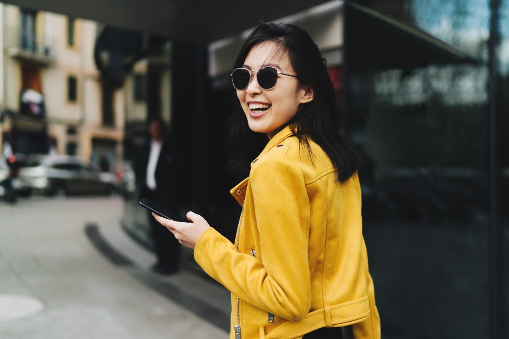 Woman on street in yellow outfit smiling