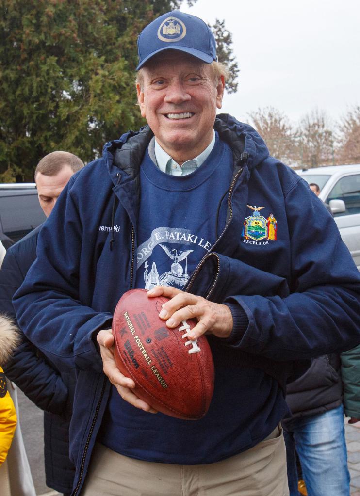 Former Republican Governor George Pataki in a hat holding a football outside