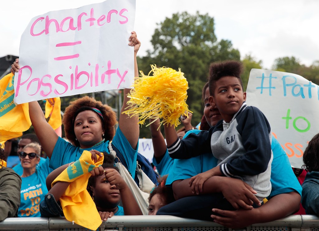 Charter school supporters in blue shirts holding signs at a rally