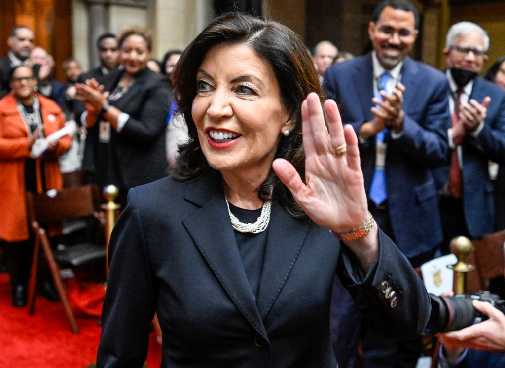 Kathy Hochul waving to people inside Assembly chambers with people clapping