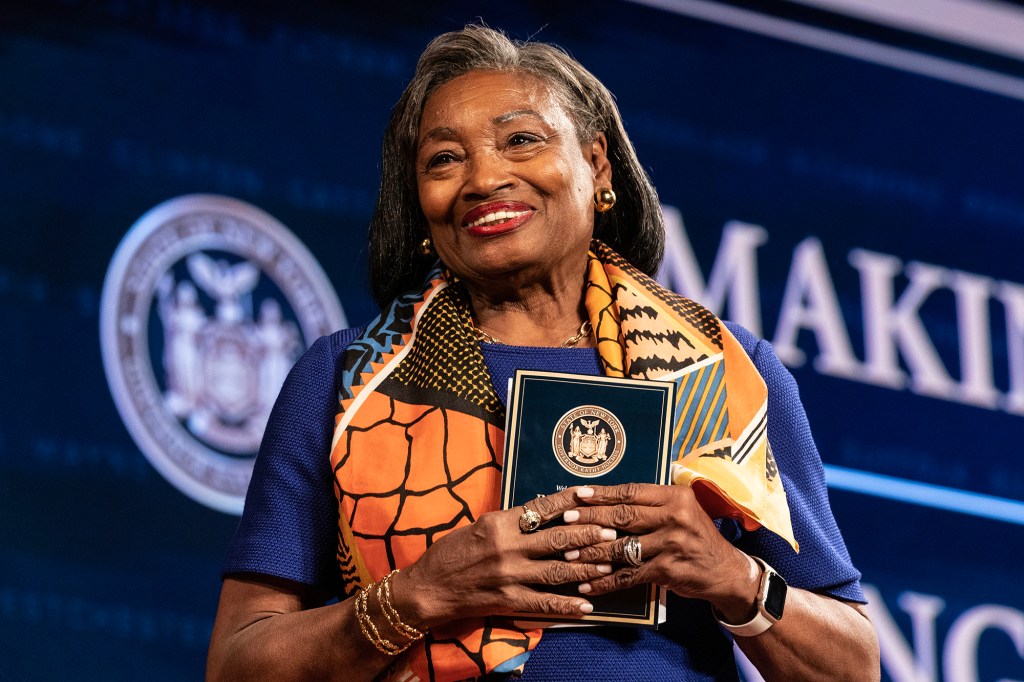 Andrea Stewart-Cousins with a trademark scarf that is pumpkin orange holding a pamplet