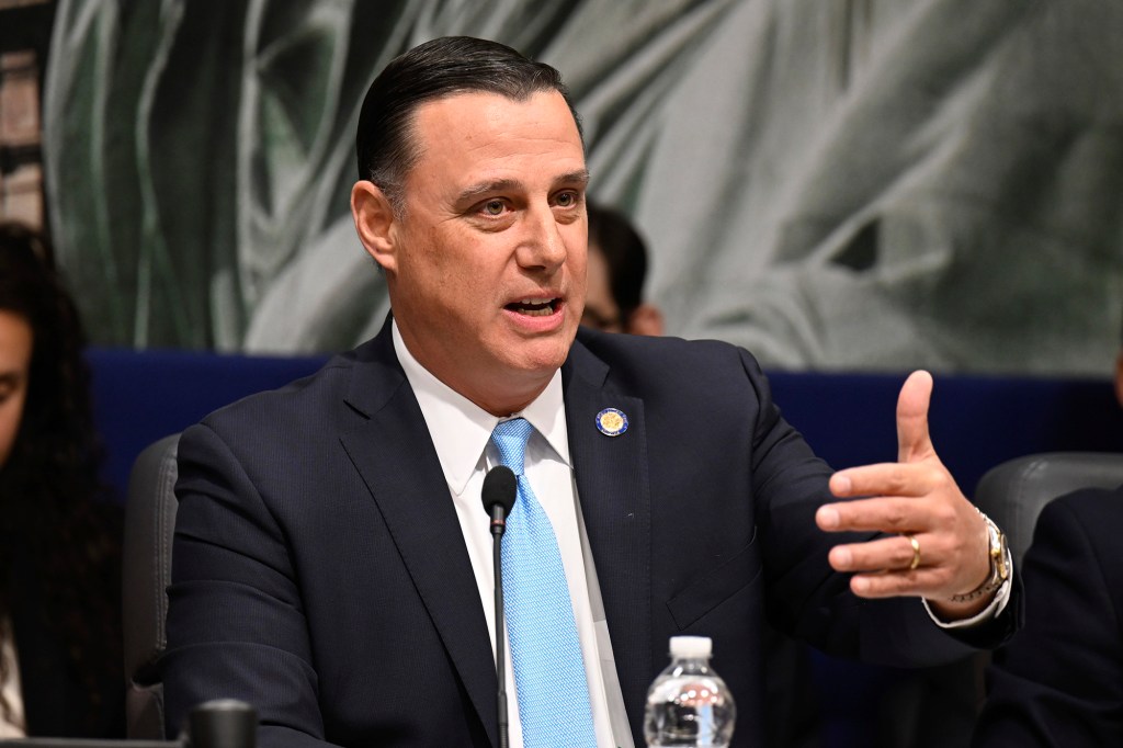 State Sen. Anthony Palumbo in a suit with blue tie speaking with a microphone at a hearing