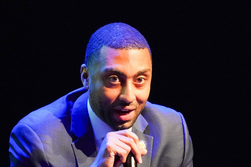 Jamaal Bailey in a dramatically lit room with purple lighting on him in front of a dark background