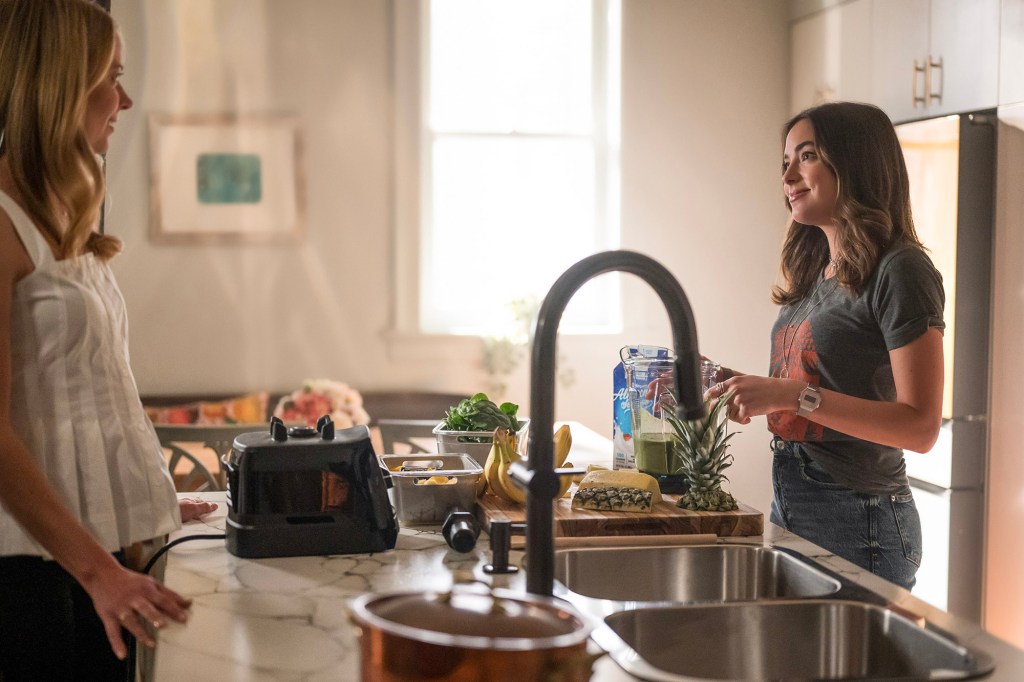 Amy Acker and Mariel Molino in "The Watchful Eye" stand in a kitchen by a sink. 