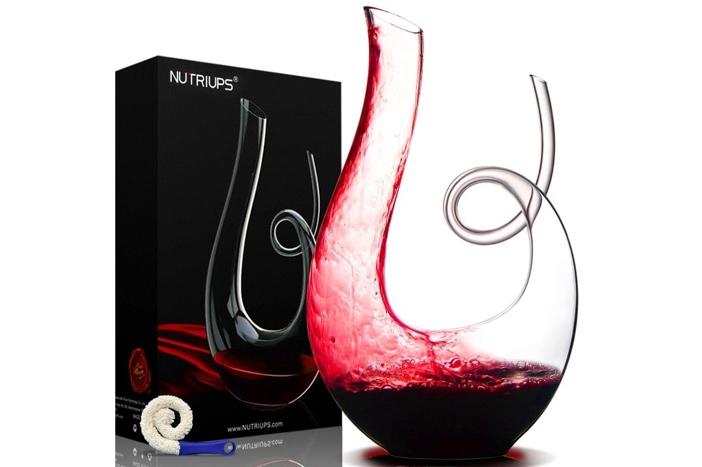 clear wine decanter with red wine poured inside in front of product box